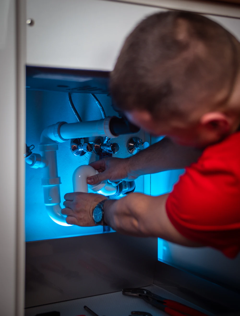 Instalatér opravuje sifon pod dřezem